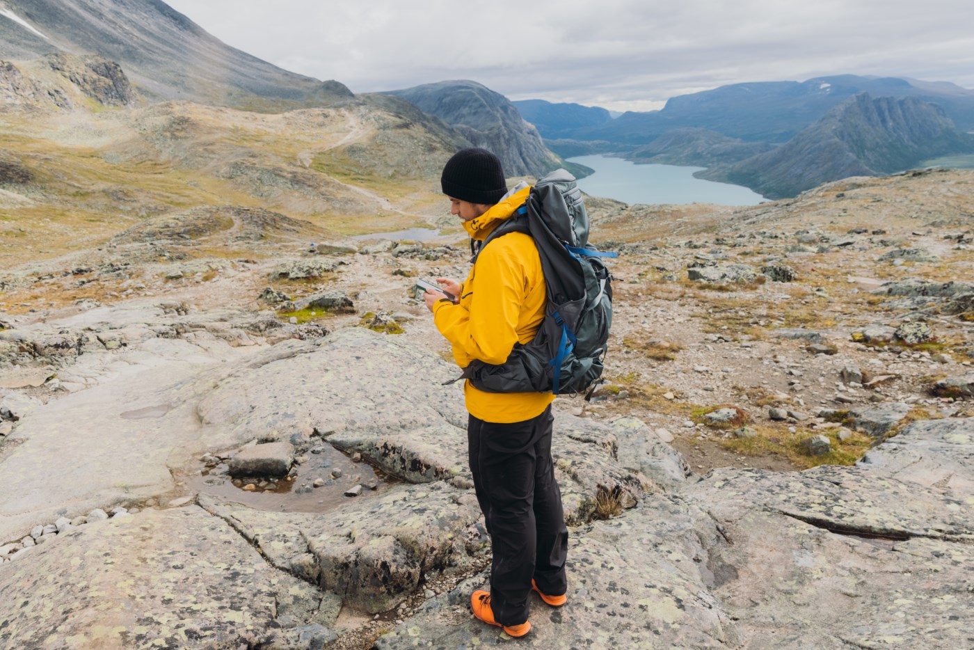 En mann som ser på telefonen sin på fjellet